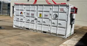 A large, white storage container with multiple latches along its side. Several orange pipes are emerging from its top.