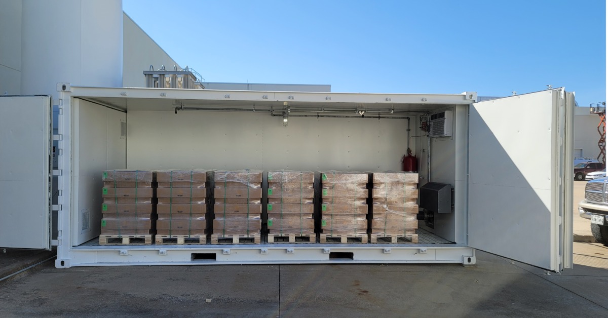 A large shipping container with it's side fully opened. There are multiple pallets of products inside the container.