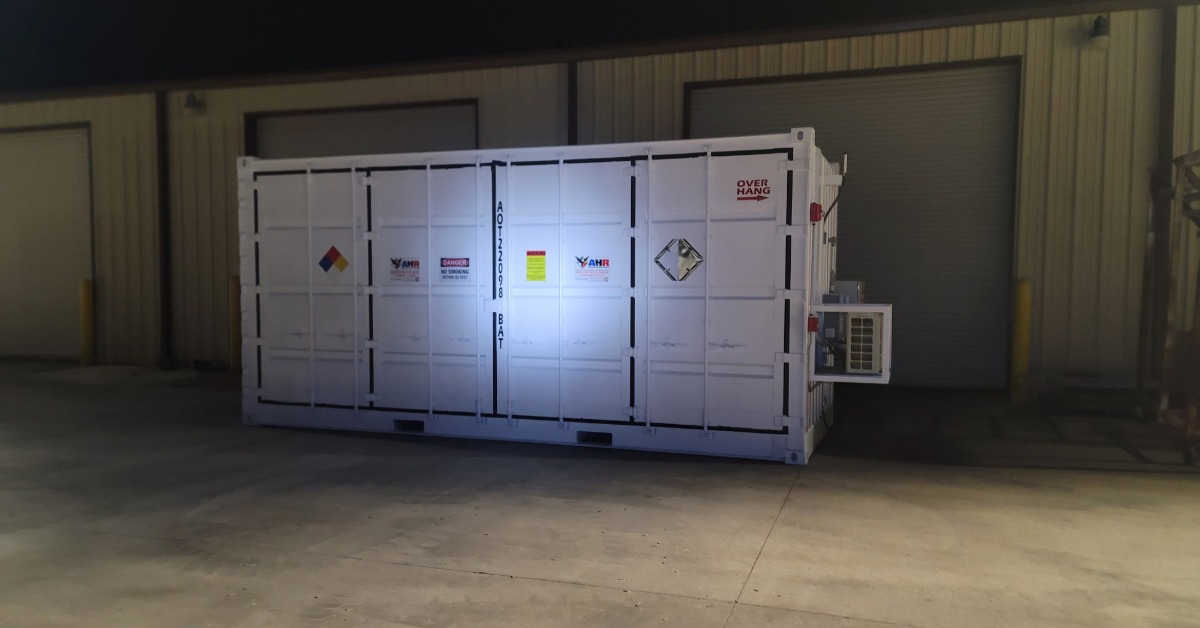A smaller, white storage container positioned at a dock. It is lit up by a flashlight's light at night.