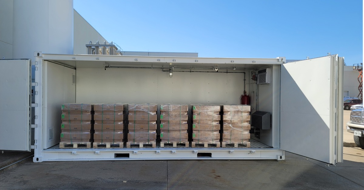 A large, white storage container with its side doors open. Inside the container are multiple pallets of products.
