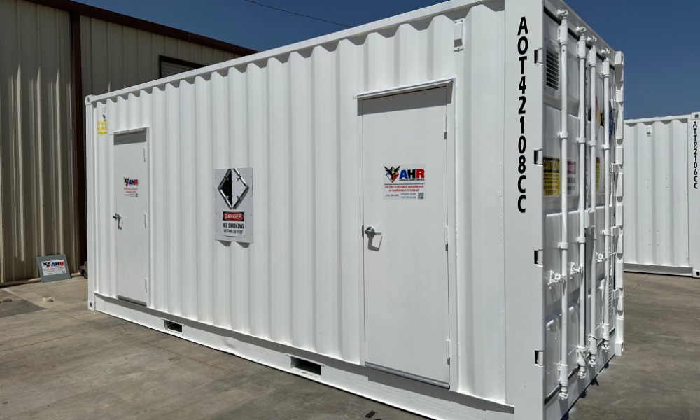 A small white storage container in a loading area. There is a variety of writing all along the sides of the container.