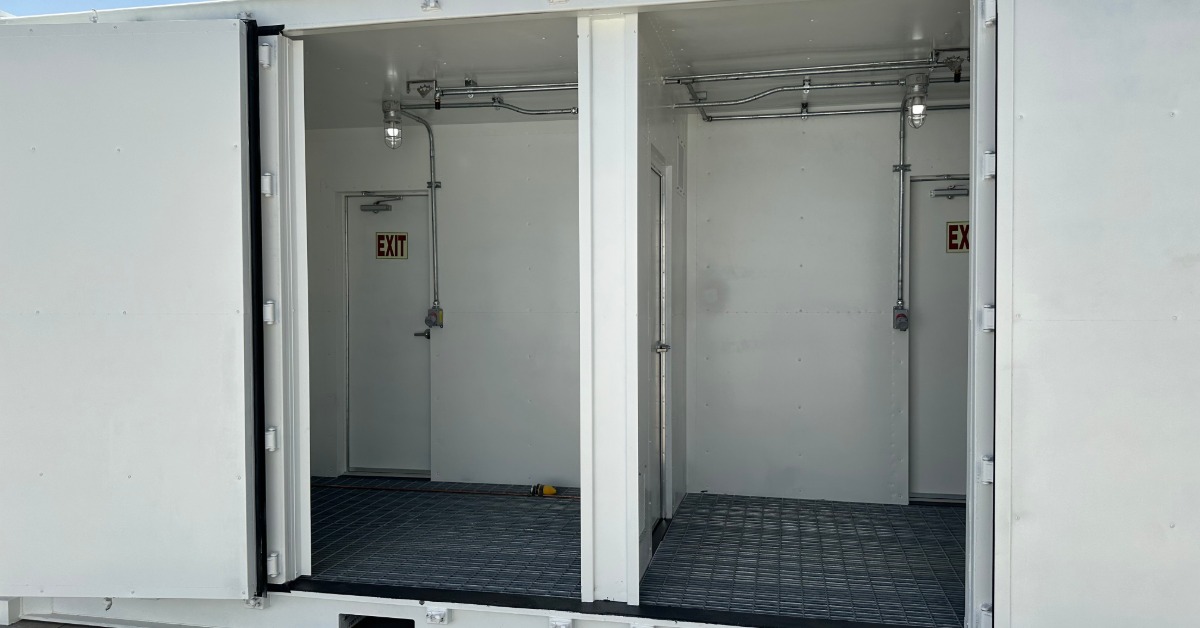 The side of a white storage container with its side doors wide open. There are exit doors in to the back of the containers.