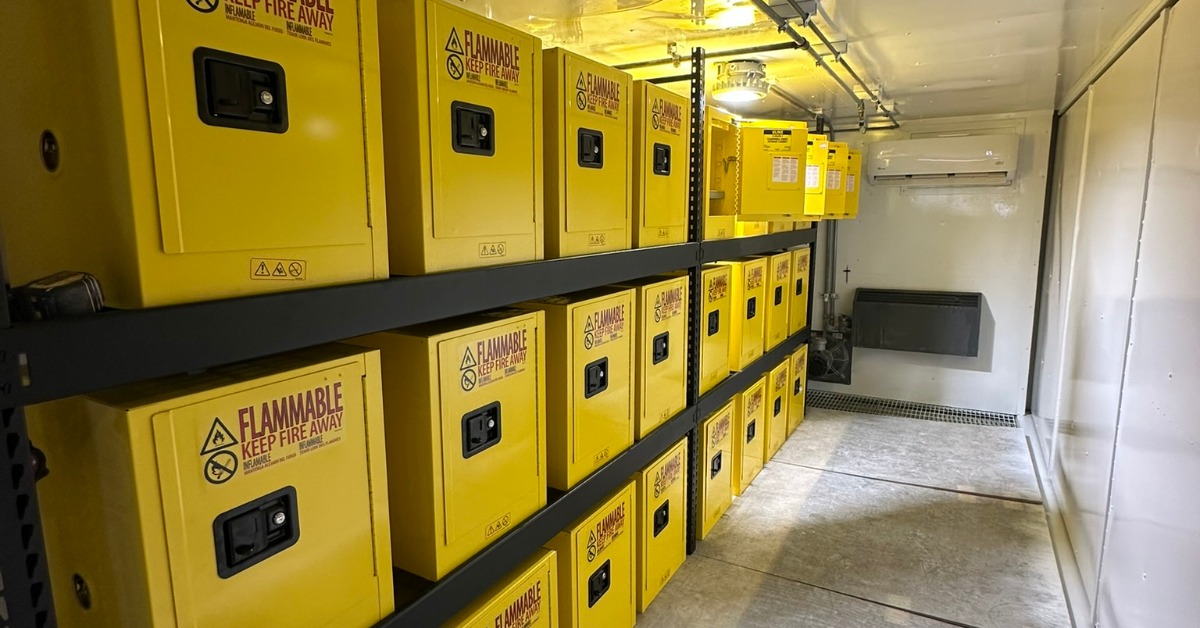 The inside of a large storage container. There are multiple lockers on the wall that have "flammable" written on them.