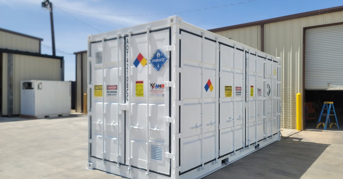 The front and side of a white storage containment unit. There are multiple warning and caution signs plastered on the sides.