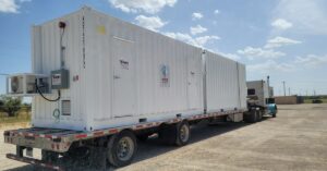 A large, white storage container placed on the bed of a truck. There is a small air conditioning unit on the container.