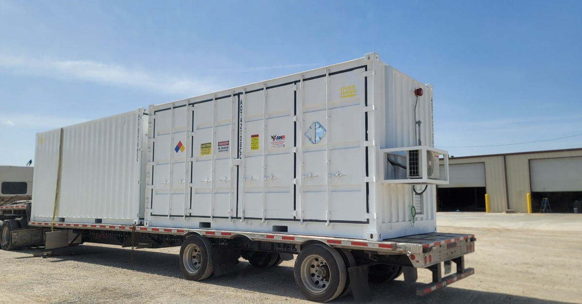 A large, white storage container positioned on the bed of a truck. The container has multiple warning symbols on it.