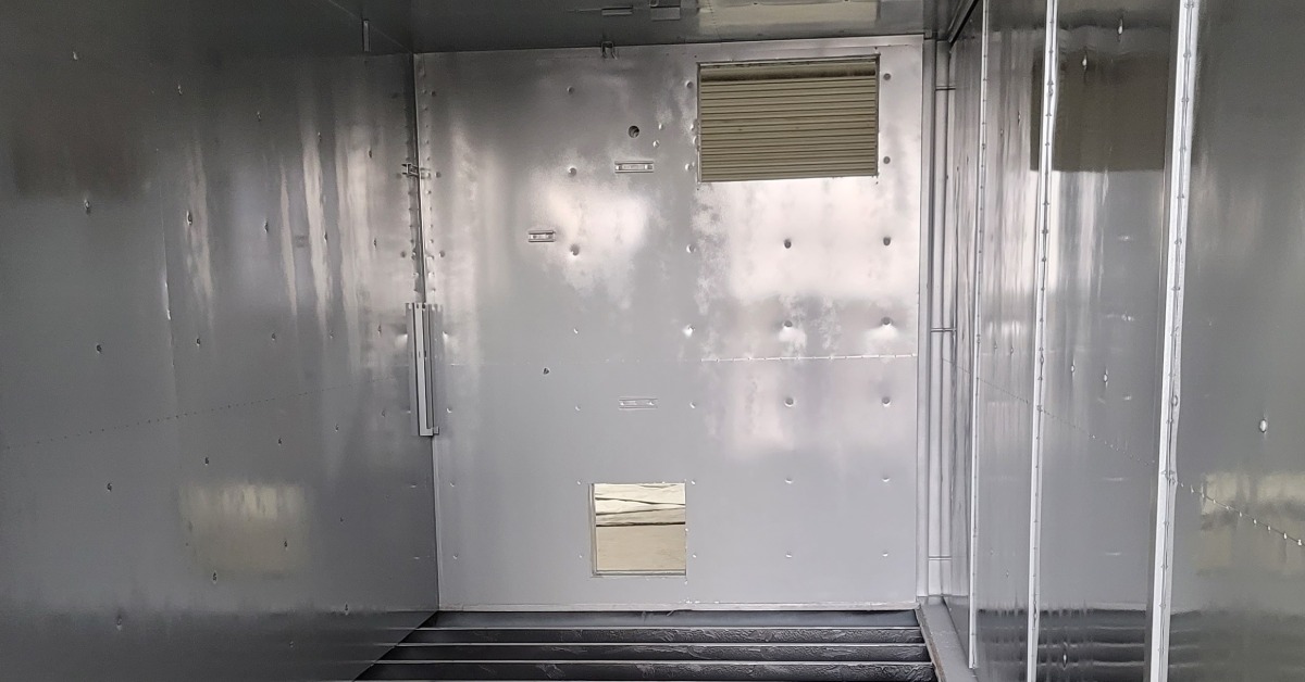 The interior of a large storage container. The floor has been removed, revealing the under structure of the container.